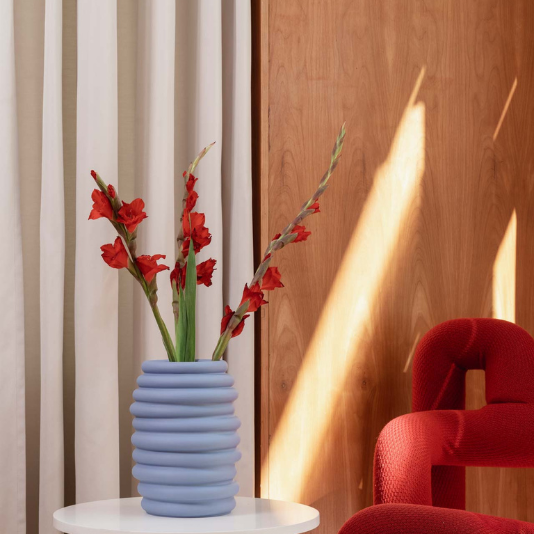 Rote Gladiolen in blauer Rosenthal Vase auf weißem Tisch im modernen Wohnzimmer